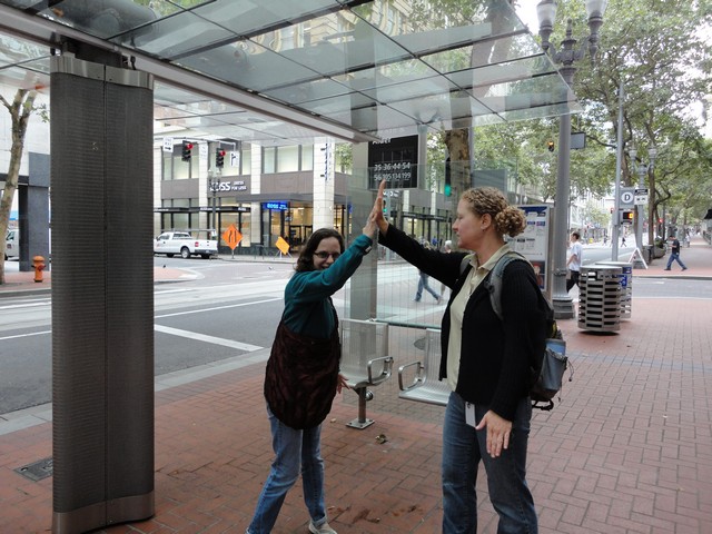 Travel trainer from RideWise and student, pictured at bus stop, share a congratulatory high-five