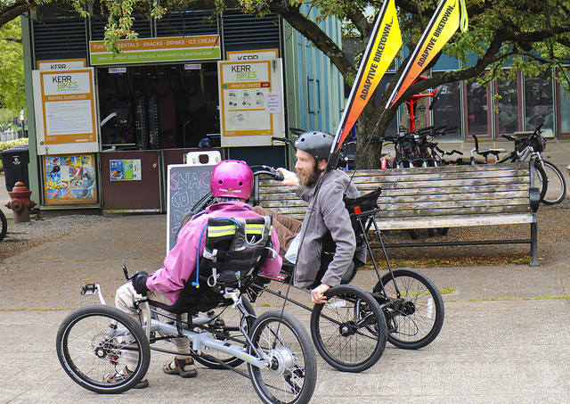 Two riders on adaptive bicycles speak with each other