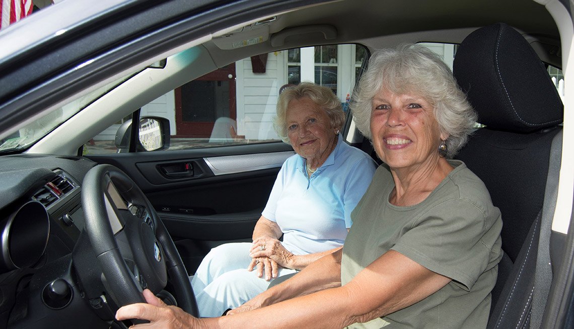 Two smiling older women in the front seats of a car.