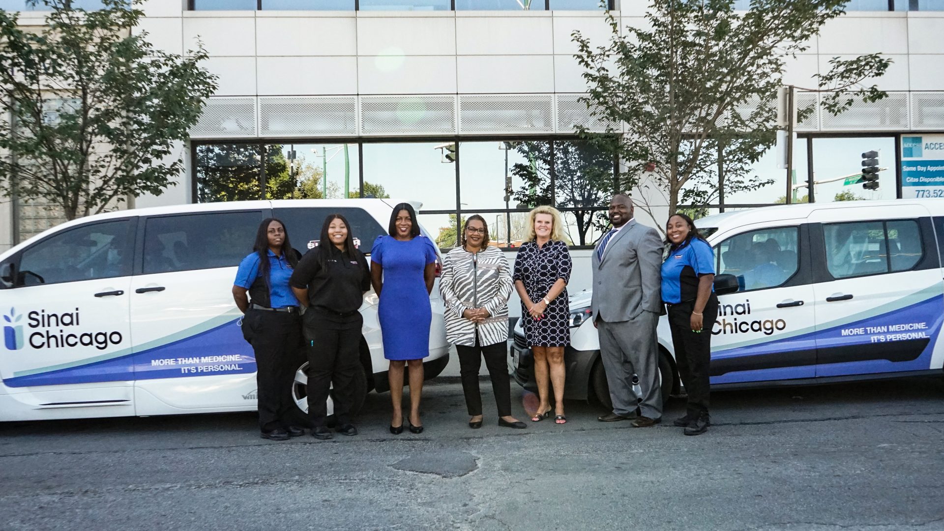 A group of Sinai Hospital employees involved with their shuttle, stand around the new service's vehicles.
